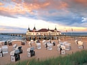 Strandkörbe vor Seebrücke bei Sonnenuntergang.