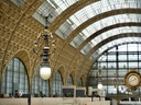 Innenansicht des Musée d'Orsay mit grosser Uhr und verzierten Bögen.