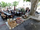Menschen sitzen auf Café-Terrasse mit Buffet im Freien.