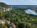 Landschaft mit Fluss, bewaldeten Hügeln und Felsen.