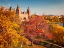 Herbstlandschaft mit Schloss und bunten Bäumen.