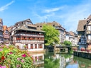 Malebene Fachwerkhäuser an einem Kanal mit Blumen und Brücke.