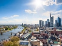 Panoramablick auf Frankfurt am Main mit Skyline, Fluss und Sonnenschein.