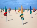 Bunte geschlossene Sonnenschirme am Strand.