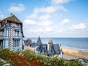 Historisches Gebäude am Meer mit Sandstrand und blauem Himmel.