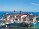 Historische Seebrücke über dem Meer, mit roten Dächern und türkisfarbenem Wasser.