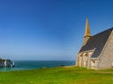 Steinkirche auf Klippen mit Meer im Hintergrund, bei klarem Himmel.