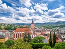 Stadtansicht mit Kirche und bewölktem Himmel.