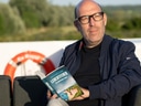 Person liest ein Buch draussen auf einem Boot.