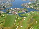 Luftaufnahme eines Golfplatzes mit umliegenden Wasserkanälen und Häusern.