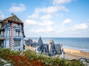 Historisches Gebäude am Meer mit Sandstrand und blauem Himmel.