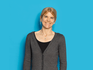 Frau mit grauem Cardigan vor blauem Hintergrund.