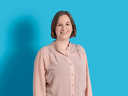 Person mit rosa Bluse vor hellblauem Hintergrund.