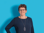 Person in dunklem Oberteil vor blauem Hintergrund.