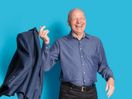 Eine Person in blauer Kleidung hält ein blaues Jackett vor einem blauen Hintergrund.