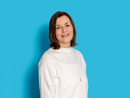 Frau in weissem Oberteil vor einem blauen Hintergrund.