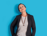 Person in schwarzem Blazer vor blauem Hintergrund.