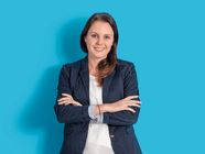 Lächelnde Person in dunkelblauer Jacke vor blauem Hintergrund.