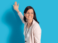 Person in rosa Jacke lehnt sich gegen eine blaue Wand.