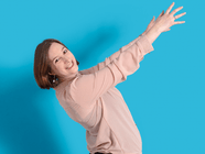 Person in rosa Hemd vor blauem Hintergrund, streckt die Arme.