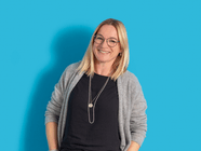 Lächelnde Person mit Brille vor blauem Hintergrund.