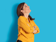 Lächelnde Person in gelbem Hemd vor blauem Hintergrund.