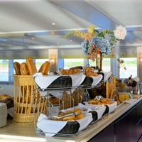 Buffettisch mit Brot und Blumenarrangement auf einem Boot oder Schiff.