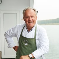 Lächelnder Mann in Kochschürze auf einem Boot.