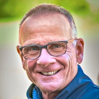 Person mit Brille und Jacke lächelt in die Kamera.