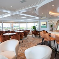 Elegante Lounge mit Tischen, Stühlen und Bar.