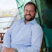 Mann sitzt lächelnd auf einem Boot.