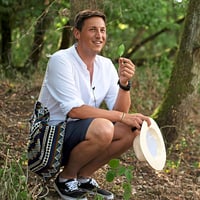 Mann im Wald, der ein Blatt hält und kniet.