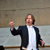 Mann in Frack singt mit ausdrucksstarker Geste.