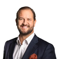 Mann im Anzug lächelt freundlich.