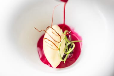 Rote Sauce wird auf Dessert in weissem Teller gegossen.