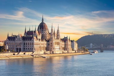 blick-auf-den-stadtteil-pest-mit-dem-kolossalen-budapester-p.jpg Grosses Gebäude am Fluss mit Hügeln im Hintergrund.