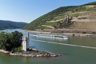 der-hybrid-flussliner-auf-dem-mittelrhein.jpg Flusskreuzfahrtschiff auf dem Rhein mit Burgruine und Weinberg im Hintergrund.