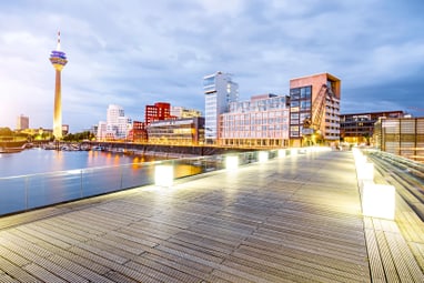 Holzsteg und beleuchtete Skyline am Abend in Düsseldorf.