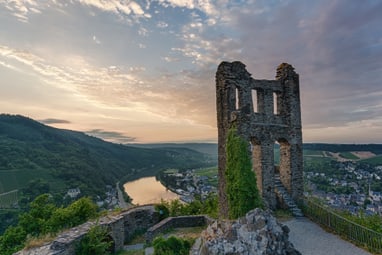 die-hoehenburgruine-grevenburg-mit-blick-ueber-die-moselschl.jpg Ruine mit Aussicht auf Fluss und Landschaft bei Sonnenuntergang.