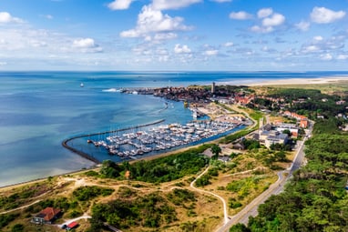 der-yachthafen-de-noordvaarder-im-naturreservat-der-wattenme.jpg Luftaufnahme eines Küstendorfes mit Yachthafen und Strand.