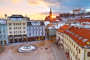 Blick auf schneebedeckten Stadtplatz mit historischen Gebäuden bei Sonnenuntergang.