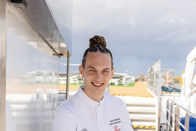 Person in weissem Outfit sitzt auf einem Bootdeck.
