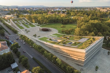 Luftaufnahme eines modernen Gebäudes mit begrüntem Dach und umliegender Parklandschaft.