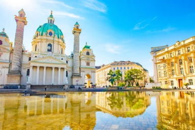 die-karlskirche-eine-der-bedeutendsten-sakralbauten-mitteleu.jpg Barockkirche und Gebäude spiegeln sich in einem Wasserbecken.