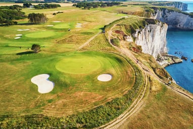 club-golf-detretat.jpg Landschaft mit Küstenklippen, grünen Feldern und Golfplätzen neben dem Meer.