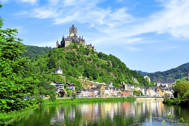 Burg auf einem Hügel über einer Stadt am Fluss.