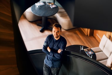 Mann steht in Wendeltreppe, lächelt nach oben.