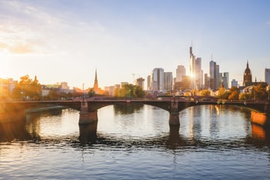 Stadtansicht mit Fluss und Brücke bei Sonnenuntergang.