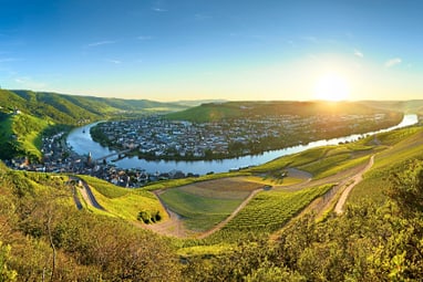 Panorama eines Flusstals mit Stadt bei Sonnenuntergang.