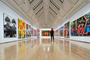 Person in Kunstgalerie mit modernen Gemälden an den Wänden.